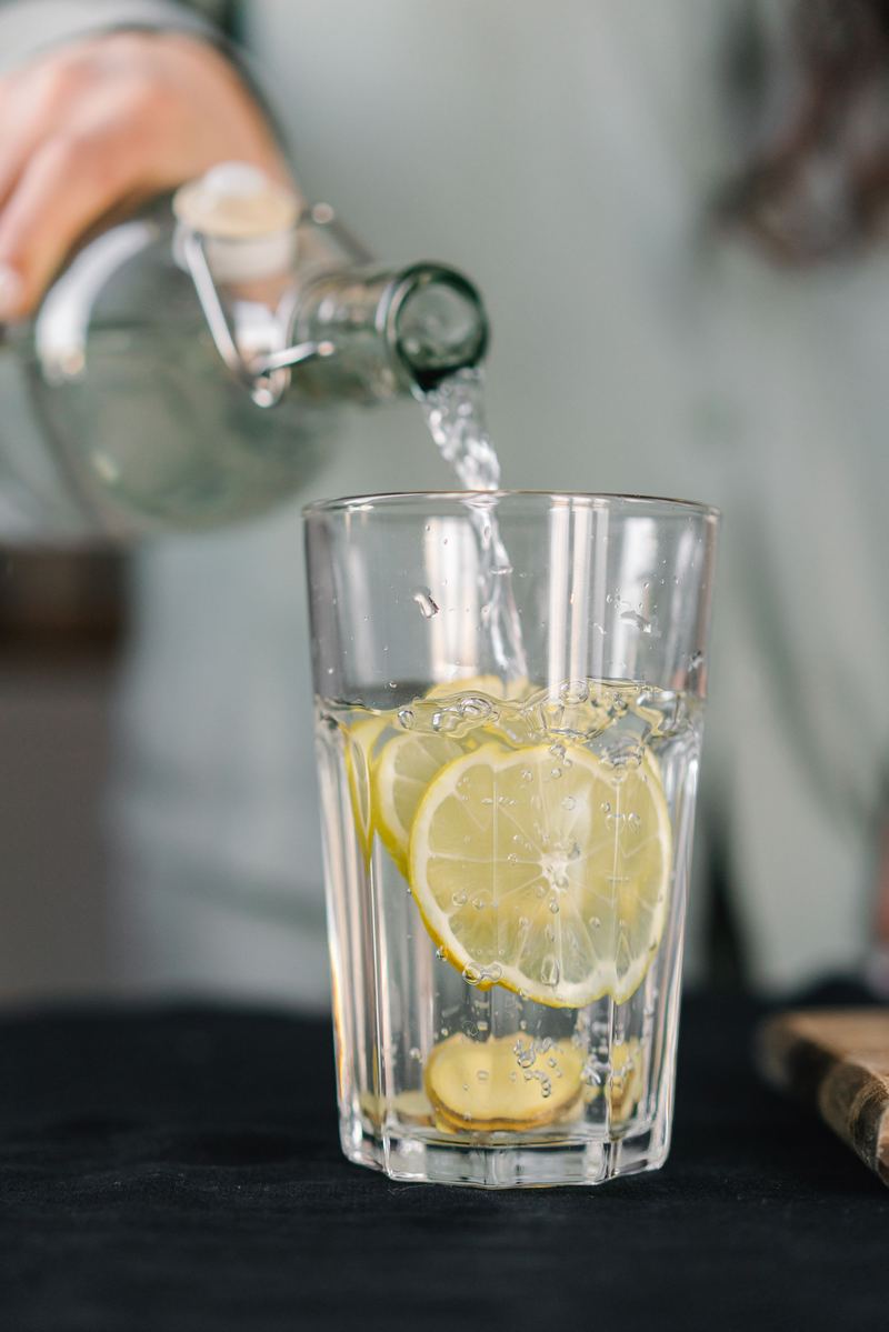 Water wordt in een glas met citroenschijfjes geschonken